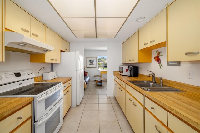 kitchen with under cabinet range hood, cream cabinets, white appliances, wood counters, and a sink