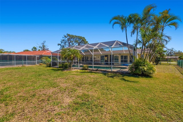 back of house with an outdoor pool, a yard, glass enclosure, and fence