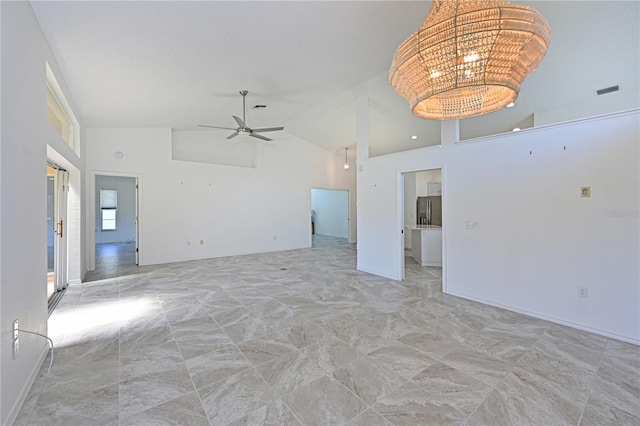empty room featuring ceiling fan with notable chandelier, high vaulted ceiling, and baseboards