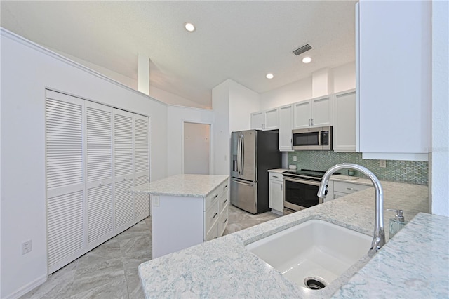 kitchen with visible vents, a sink, a kitchen island, stainless steel appliances, and decorative backsplash