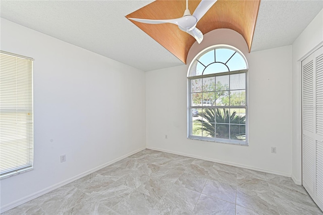 spare room with baseboards, lofted ceiling, and a textured ceiling