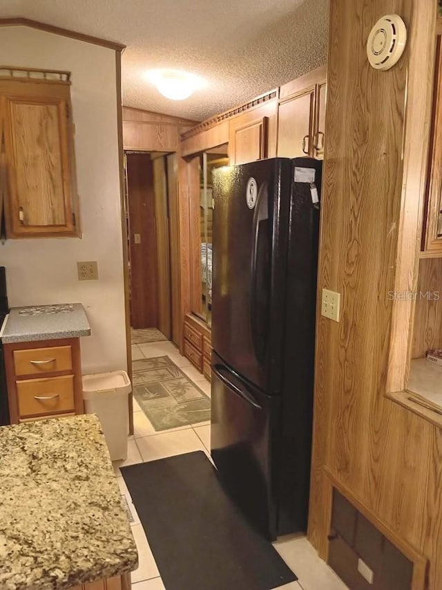 kitchen featuring a textured ceiling, light countertops, and freestanding refrigerator