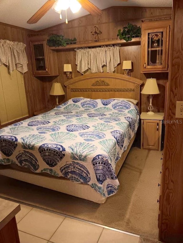 bedroom with light tile patterned floors, a ceiling fan, and wood walls