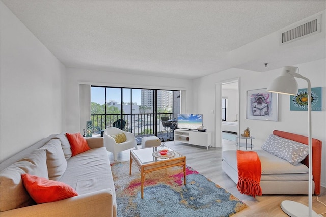 living room featuring wood finished floors, visible vents, and a textured ceiling