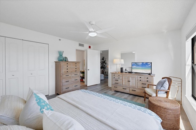 bedroom featuring visible vents, wood finished floors, a closet, a textured ceiling, and a ceiling fan