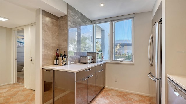 kitchen featuring stainless steel appliances, tasteful backsplash, modern cabinets, and light countertops