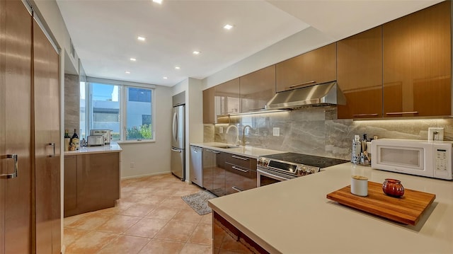 kitchen with under cabinet range hood, decorative backsplash, appliances with stainless steel finishes, modern cabinets, and a sink