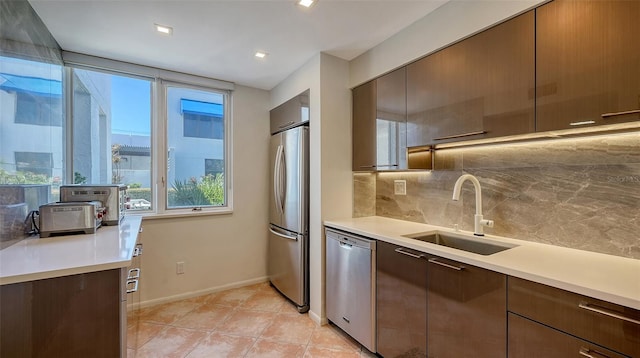 kitchen featuring backsplash, light countertops, light tile patterned floors, appliances with stainless steel finishes, and a sink