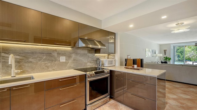 kitchen featuring white microwave, under cabinet range hood, stainless steel range with electric cooktop, modern cabinets, and a sink