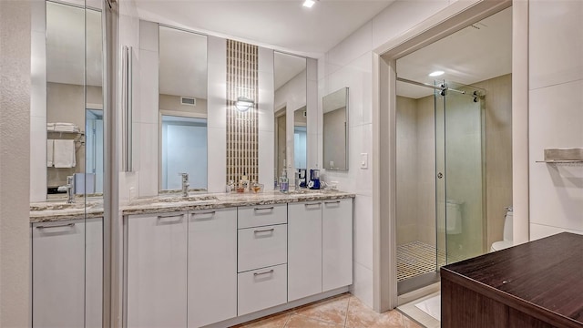 full bath with tile patterned floors, visible vents, a sink, a shower stall, and double vanity