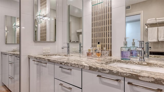 full bathroom with double vanity, visible vents, and a sink