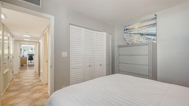 bedroom featuring light tile patterned floors, visible vents, and a closet