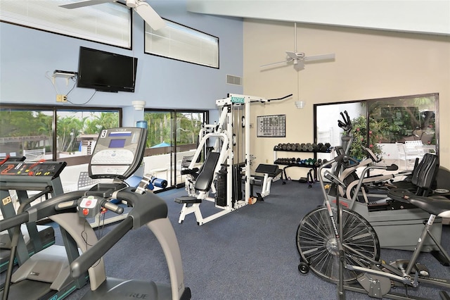 gym with a high ceiling, visible vents, and ceiling fan