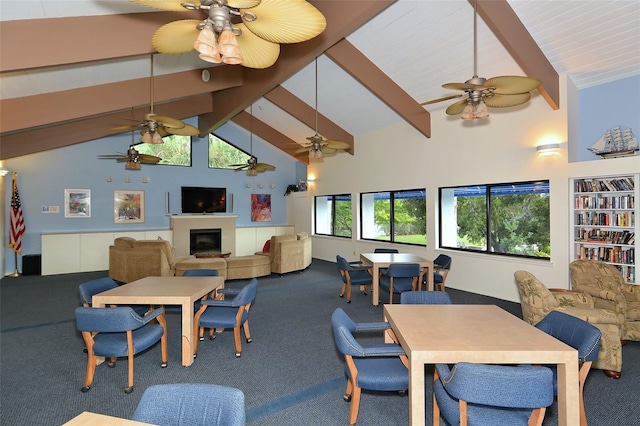 carpeted dining room featuring beamed ceiling, a fireplace, high vaulted ceiling, and ceiling fan