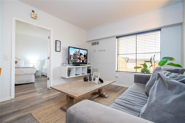 living room featuring wood finished floors, visible vents, and baseboards