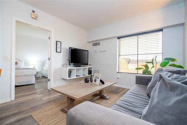 living room featuring wood finished floors, visible vents, and baseboards