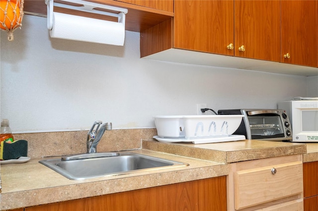 kitchen featuring a toaster, light countertops, and a sink