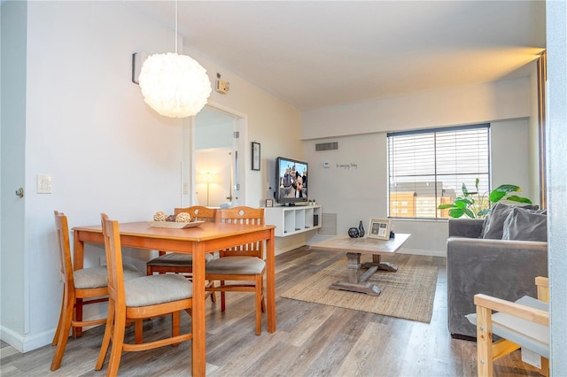 dining room featuring an inviting chandelier, baseboards, visible vents, and light wood finished floors