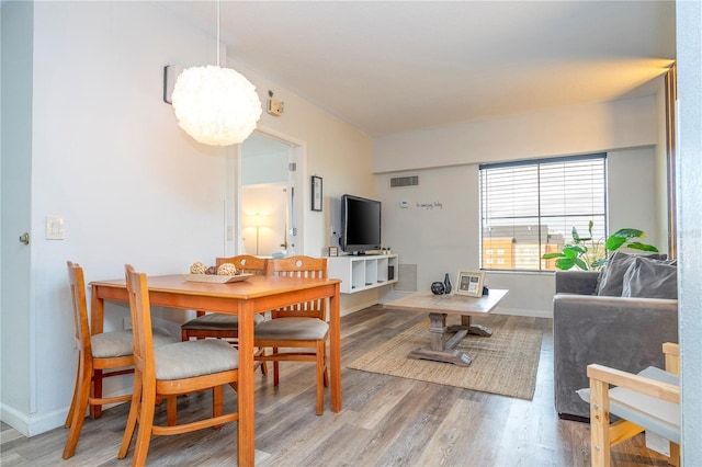 dining space with baseboards, visible vents, light wood finished floors, and a chandelier