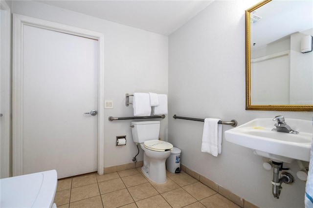 bathroom with tile patterned flooring, toilet, baseboards, and a sink