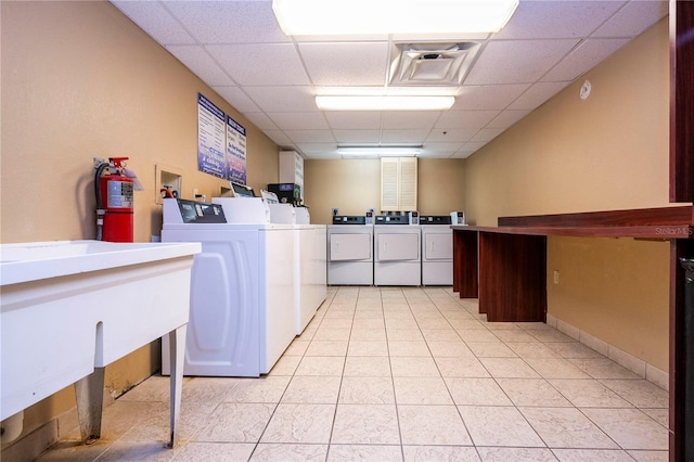 shared laundry area featuring light tile patterned floors, visible vents, baseboards, and separate washer and dryer