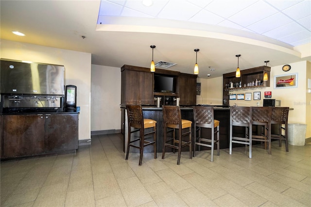 interior space featuring decorative light fixtures, visible vents, wet bar, and baseboards