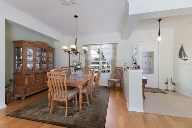 dining area with visible vents, crown molding, an inviting chandelier, and wood finished floors