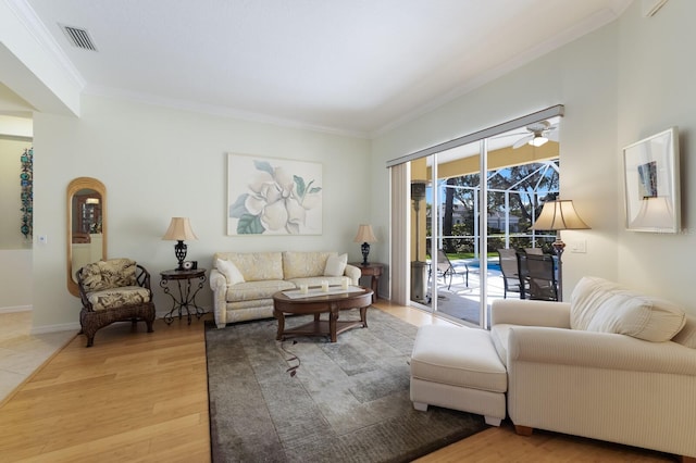 living area with visible vents, light wood finished floors, ornamental molding, a sunroom, and baseboards