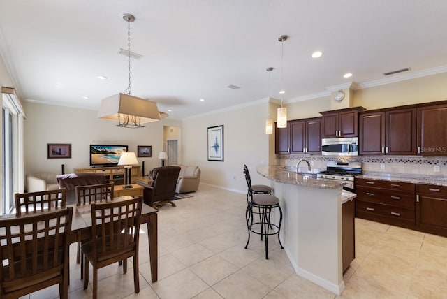 kitchen with backsplash, open floor plan, appliances with stainless steel finishes, a breakfast bar area, and crown molding