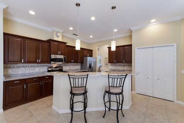 kitchen with an island with sink, decorative light fixtures, a kitchen breakfast bar, stainless steel appliances, and dark brown cabinetry