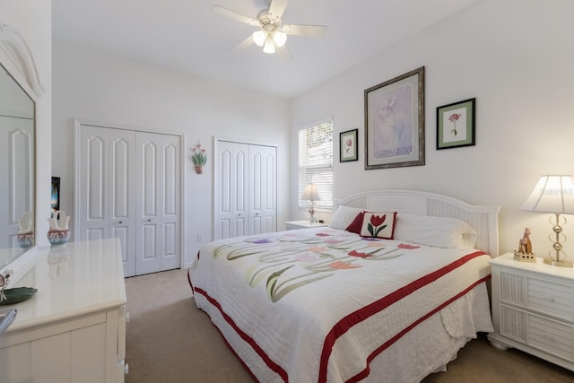 bedroom featuring light colored carpet, multiple closets, and ceiling fan