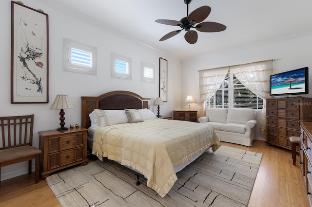 bedroom with baseboards, ornamental molding, a ceiling fan, and light wood finished floors