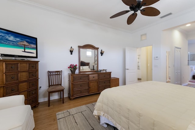 bedroom featuring a ceiling fan, visible vents, baseboards, light wood-style floors, and crown molding