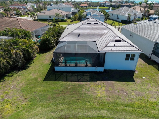 back of house featuring glass enclosure, a lawn, a residential view, and stucco siding