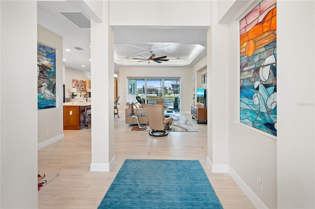 interior space with light wood-style floors, visible vents, coffered ceiling, and baseboards