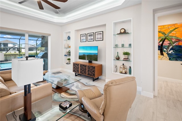 living area featuring built in features, a ceiling fan, baseboards, light wood finished floors, and a sunroom