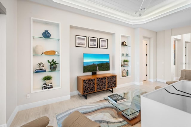 living room with a tray ceiling, built in features, wood finished floors, and baseboards