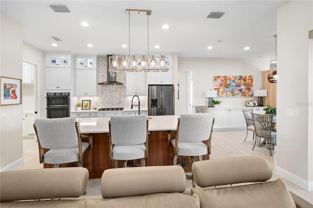 kitchen with visible vents, appliances with stainless steel finishes, decorative backsplash, and wall chimney range hood