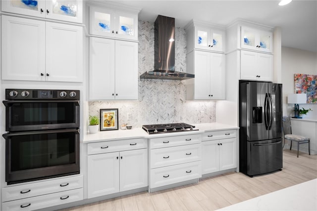 kitchen with white cabinetry, black appliances, wall chimney exhaust hood, and light countertops