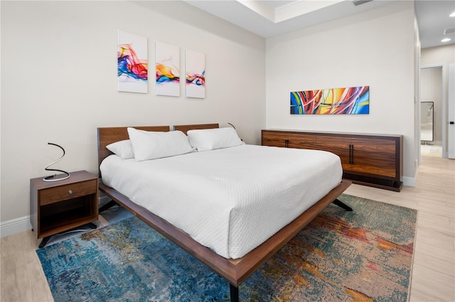 bedroom with visible vents, baseboards, and wood finished floors