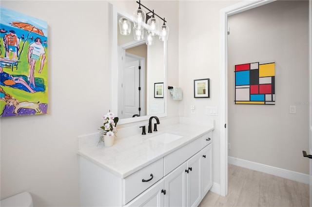 bathroom with baseboards, wood finished floors, and vanity