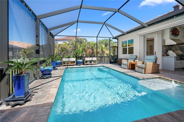 pool featuring a patio area, glass enclosure, and an outdoor kitchen