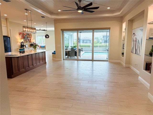6208 Signature Pointe Ln, Bradenton, FL 34210 - kitchen with a raised ceiling, black fridge, ceiling fan, light wood-style flooring, and open floor plan