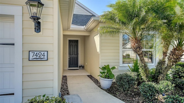 doorway to property with a garage and roof with shingles