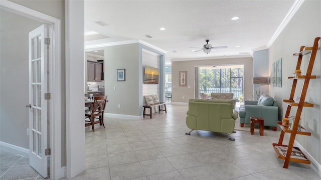 living area featuring visible vents, ornamental molding, a textured ceiling, light tile patterned flooring, and baseboards