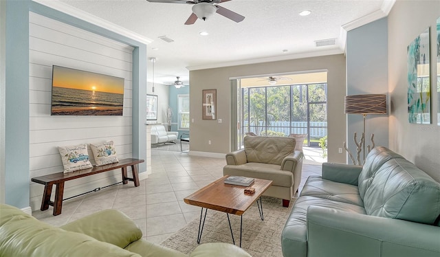 living room with light tile patterned floors, visible vents, a textured ceiling, and crown molding