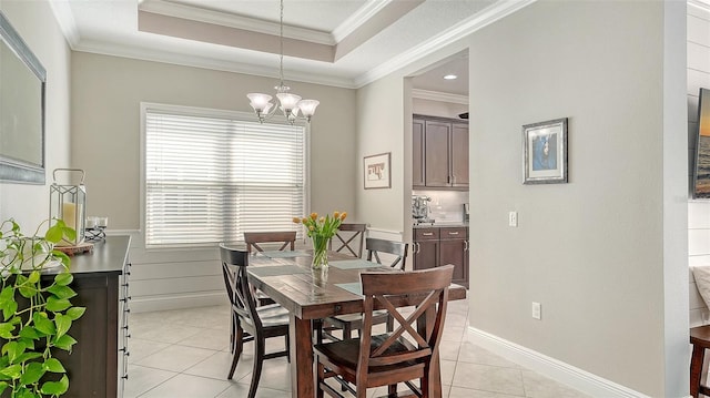 dining area with light tile patterned floors, baseboards, ornamental molding, a raised ceiling, and a notable chandelier