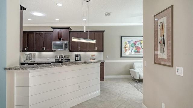 kitchen featuring visible vents, ornamental molding, dark brown cabinets, appliances with stainless steel finishes, and backsplash