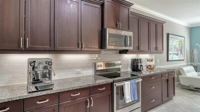 kitchen with ornamental molding, dark brown cabinetry, appliances with stainless steel finishes, stone counters, and light tile patterned floors