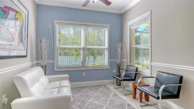 living area with tile patterned flooring, a ceiling fan, crown molding, and baseboards